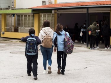 Drei Kinder gehen in ein Schulgebäude