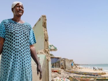Frau steht vor einer Ruine am Meer