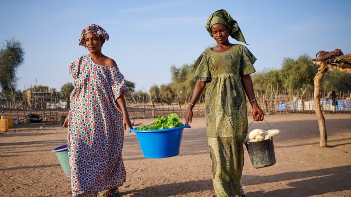 Zwei Frau tragen Früchte und Gemüse in Plastikeimern